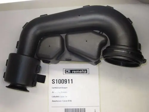 Schwarzes Bauteil von Remeha, das Teil eines Luftzufuhrsystems ist. Das Teil hat verschiedene Anschlüsse und eine gewinkelte Form zur Luftführung.